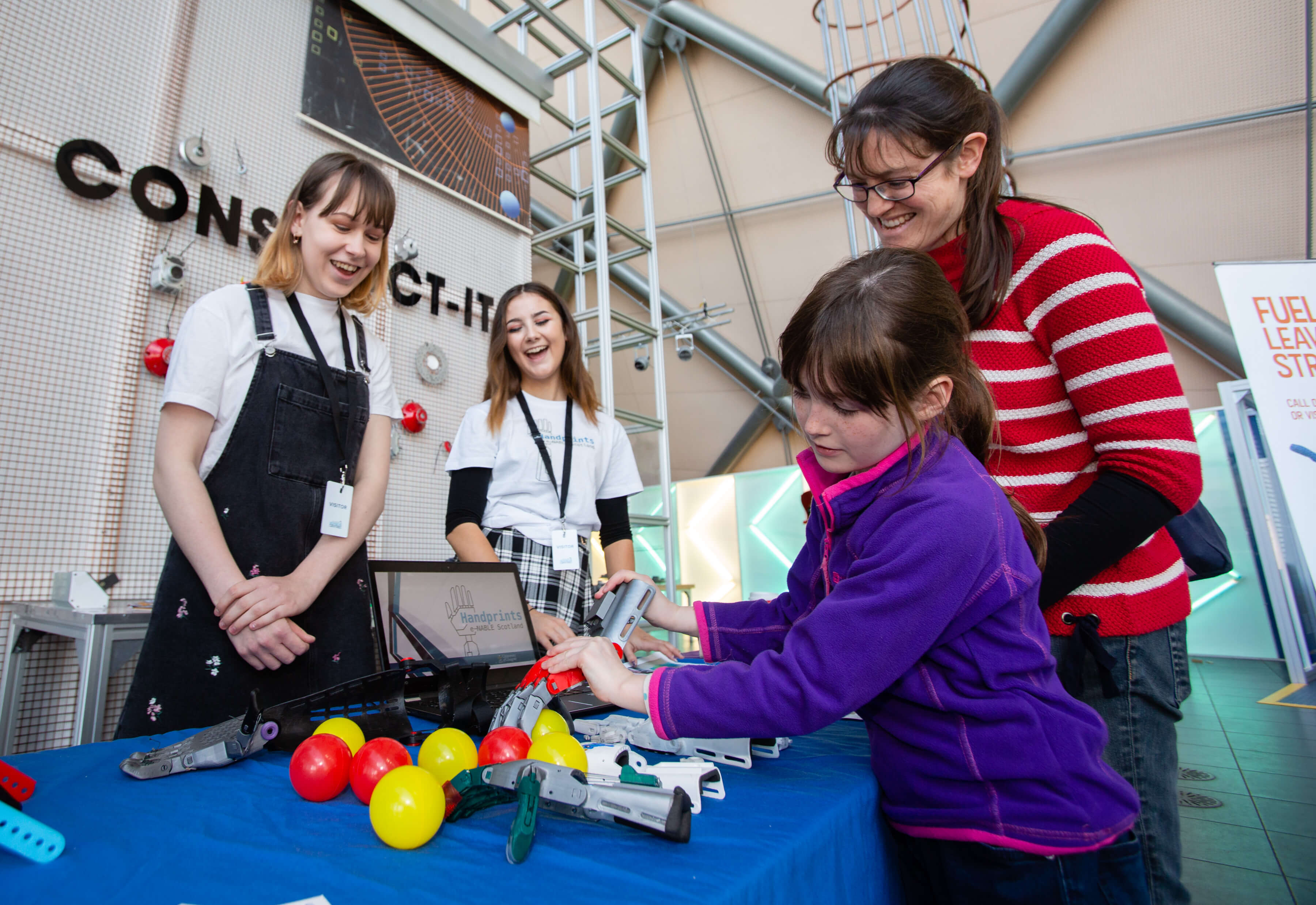 Picture showing an adult and child engaging with engineering kit at a festival stall with facilitators