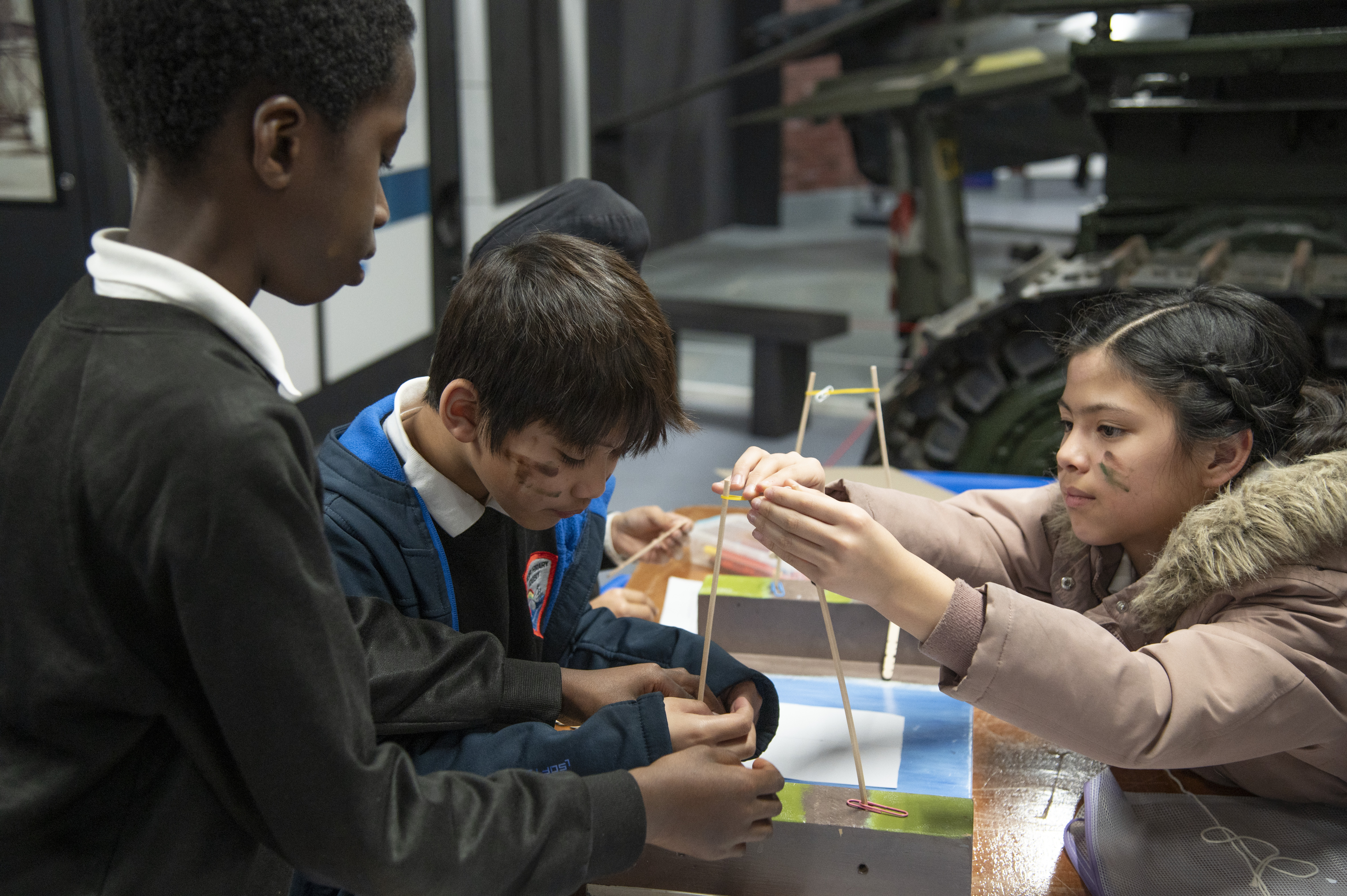 Three students building a bridge with sticks
