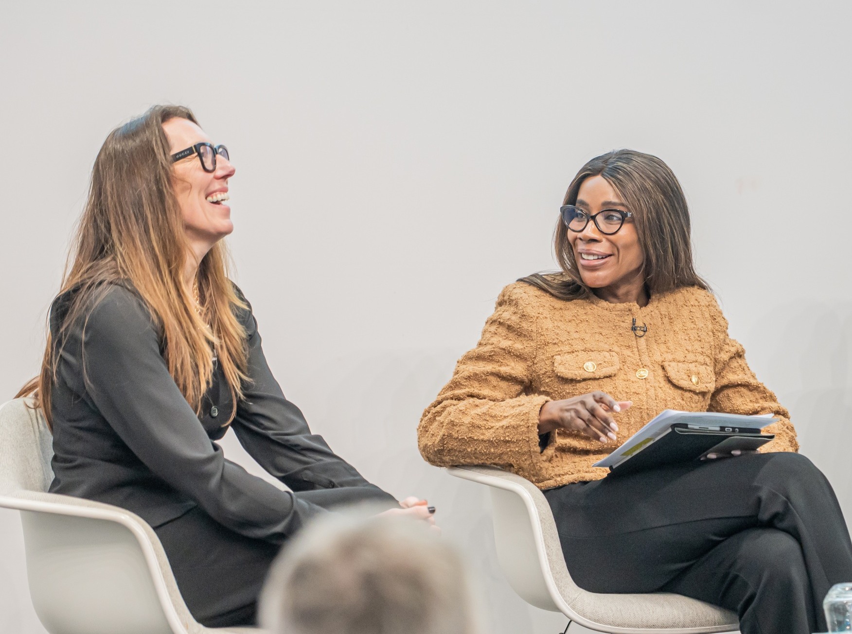 Panellists laughing and smiling on stage, wearing business attire.