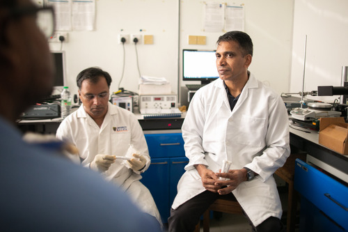 Photo of Vengadesh sitting in a lab with a colleague.