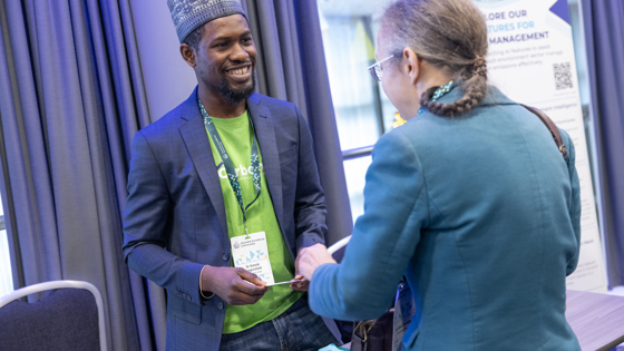 Two attendees talk at a conference exhibition stall