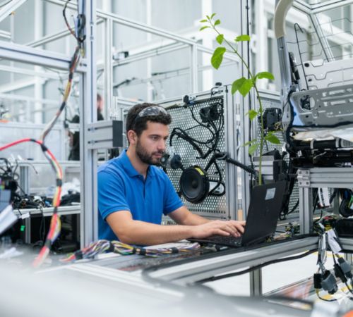 Man wearing a blue top surrounded by engineering equipment.