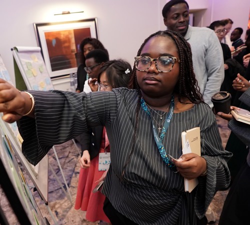 Participant adding notes to a feedback board while others gather around during a workshop.