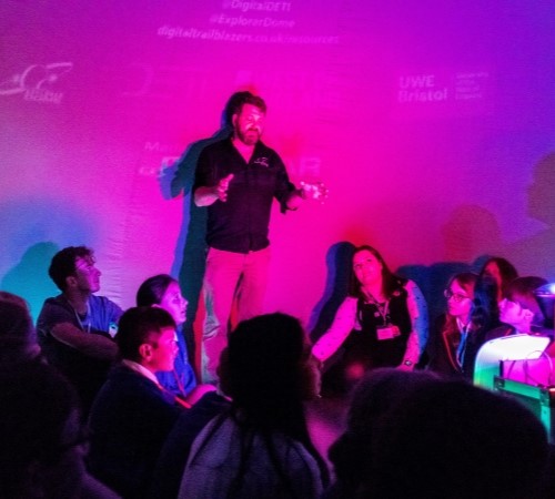 A presenter standing in the middle of students during a planetarium show