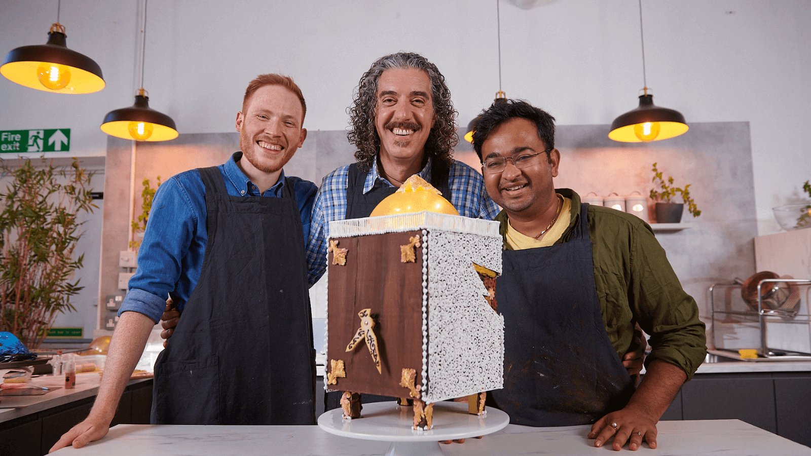 Great British Bake Off engineers (L–R) Andrew Smyth, Dr Giuseppe Dell’Anno and Dr Rahul Mandal with the working clock cake that they baked for National Engineering Day in 2022