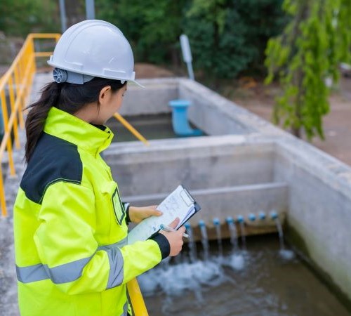 A woman in a hard hat surveying a sewage treatment plant