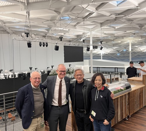 Four people posing for a photo inside a large industrial-style venue.
