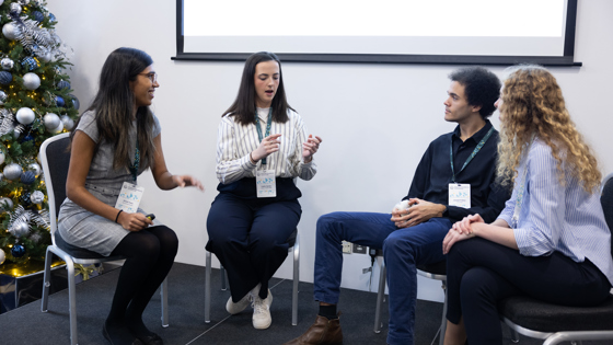 Four people sit on chairs on a stage in discussion