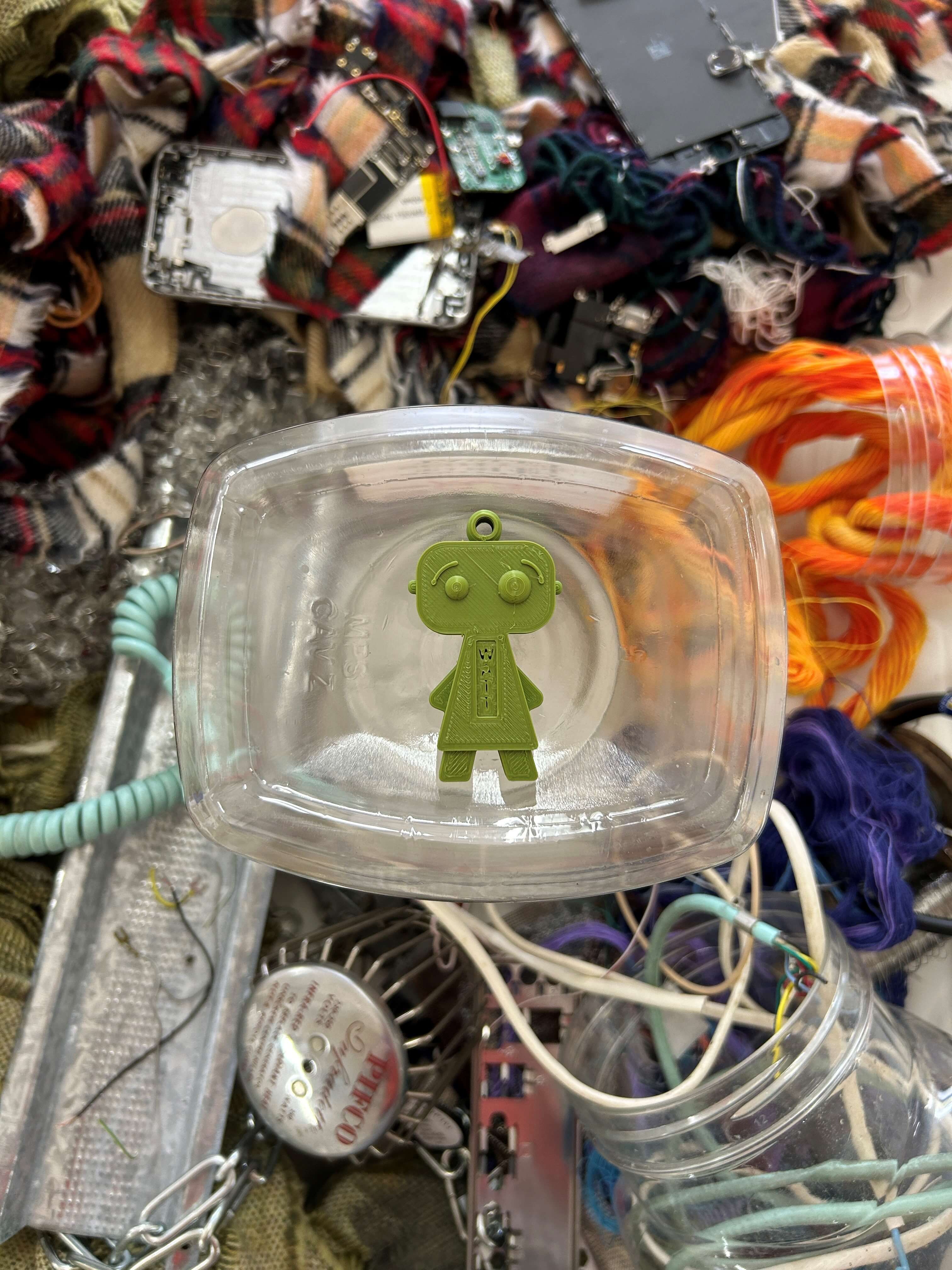 Picture of a small 3D printed robot sat amongst rubbish