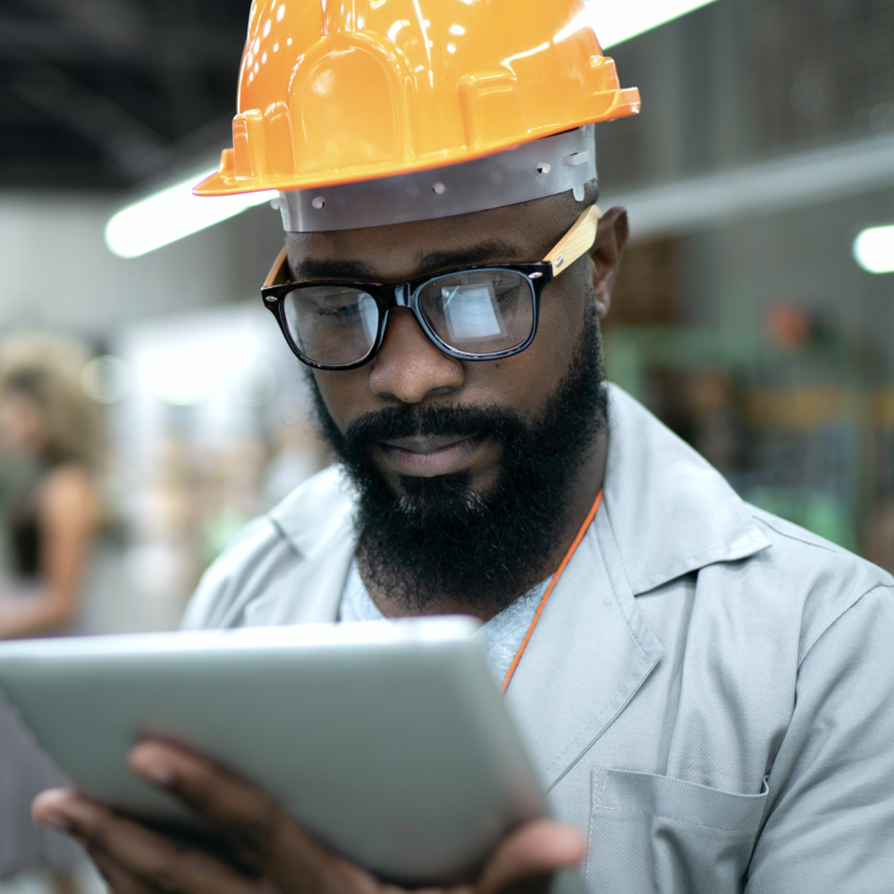 Black male engineer in helmet with tablet