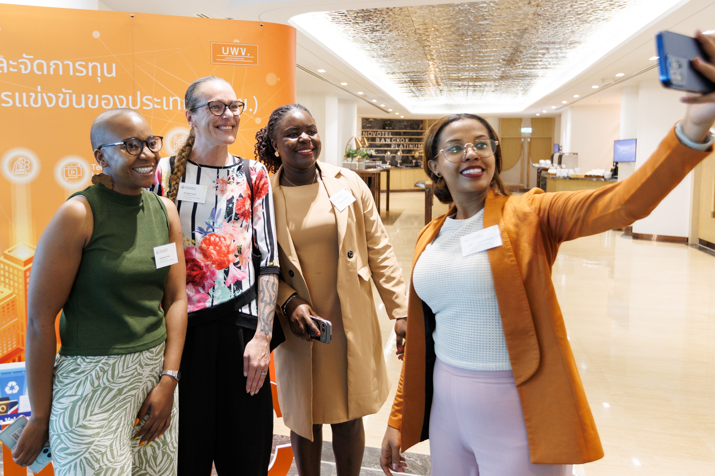 Four conference attendees taking a group selfie at a networking event.
