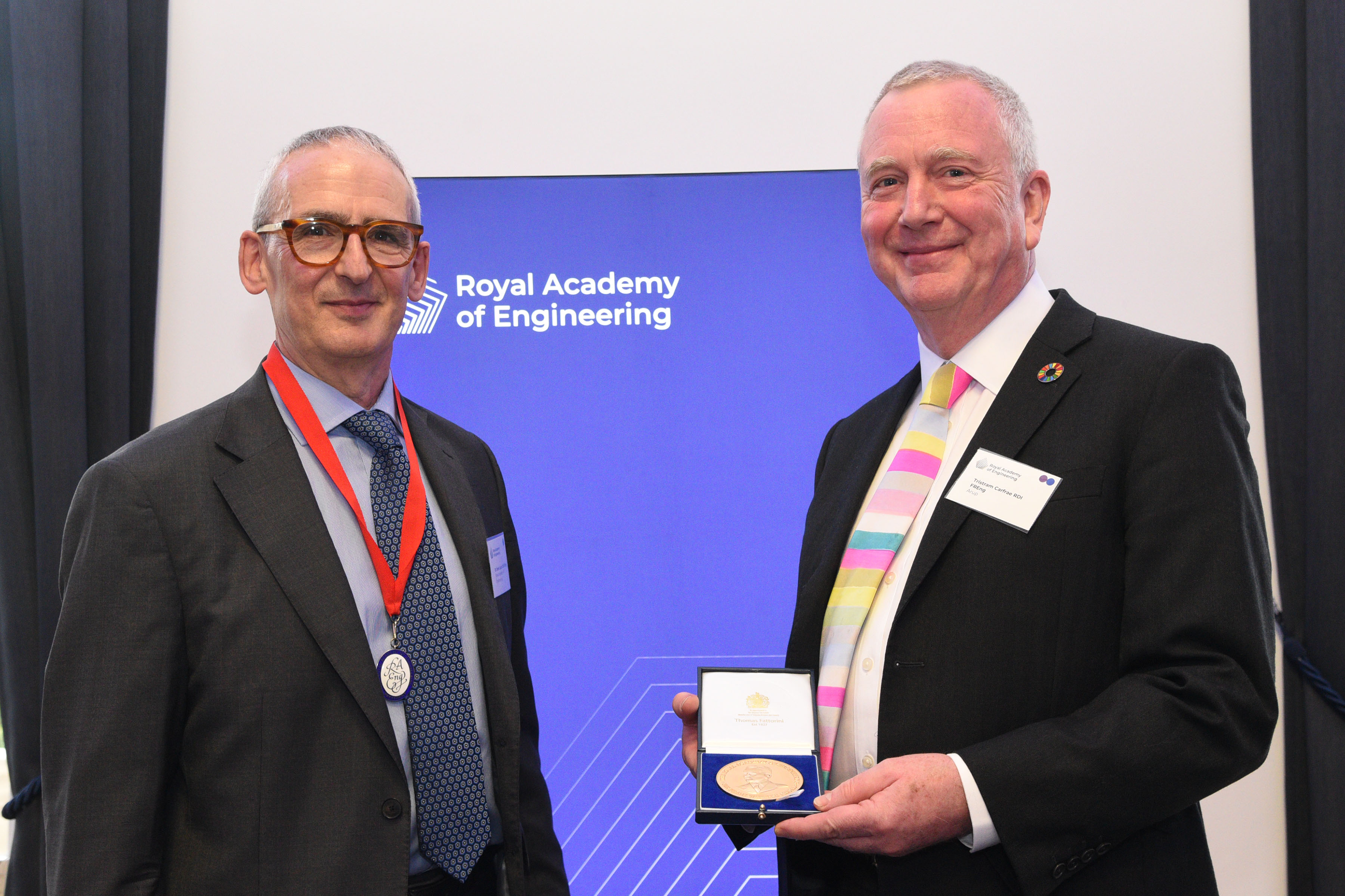 Academy President Dr John Lazar (L) presenting the Sir Frank Whittle Medal to Tristram Carfrae (R). Both are stood smiling and facing towards the camera.