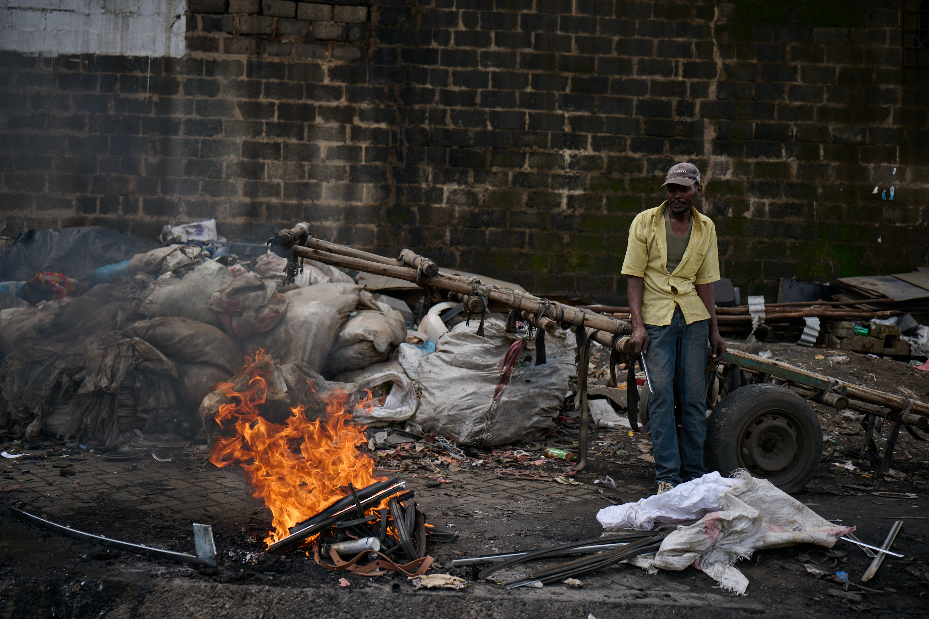 A man standing near to a pile of burning waste.