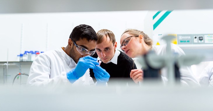 Three engineers in a lab looking at a blood sample