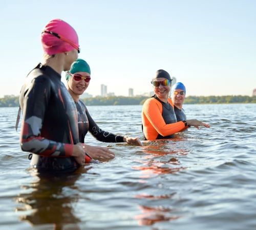 Four people swimming in wetsuits in an open body of water