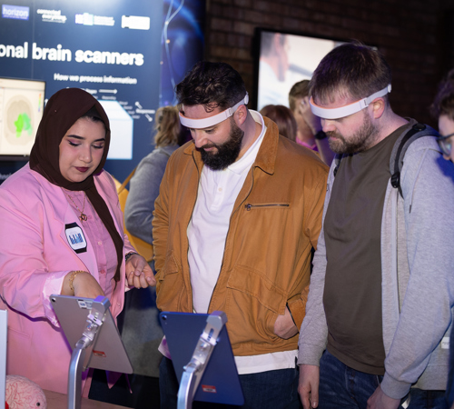 People trying a brain-scanning technology demonstration at an exhibition stand.