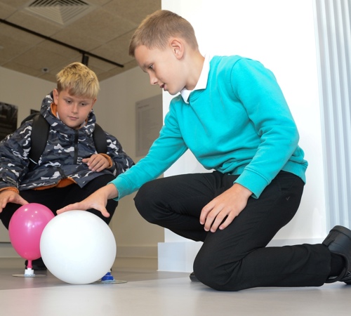 Two school pupils testing an activity with balloons on the floor.