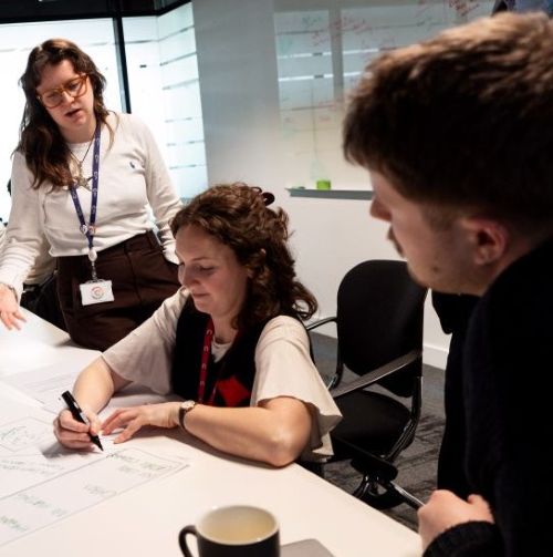 Two participants and an Academy staff facilitator working through a systems thinking exercise at a Systems 101 workshop