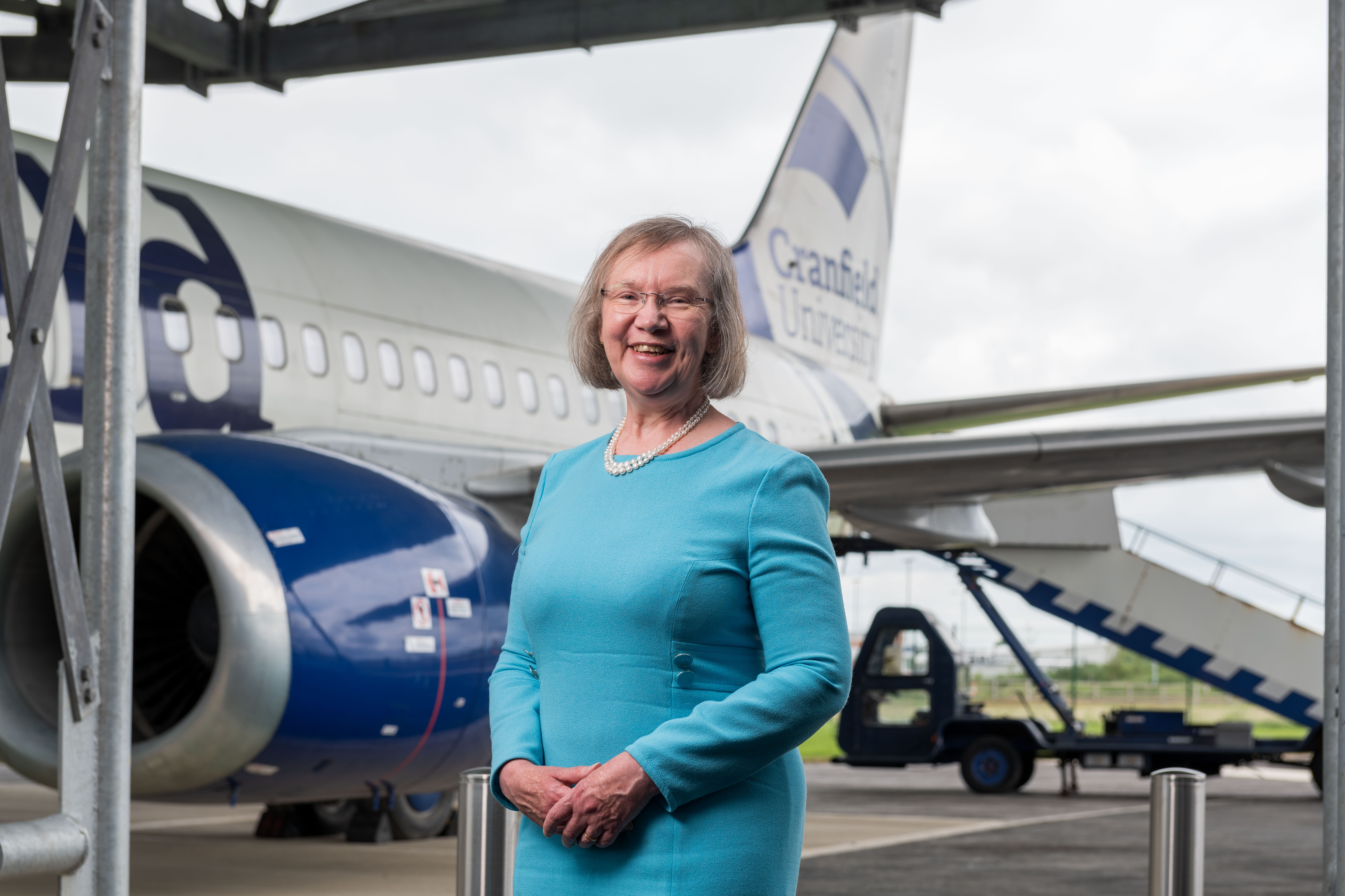 Dame Helen Atkinson stands in front of a Cranfield University plane